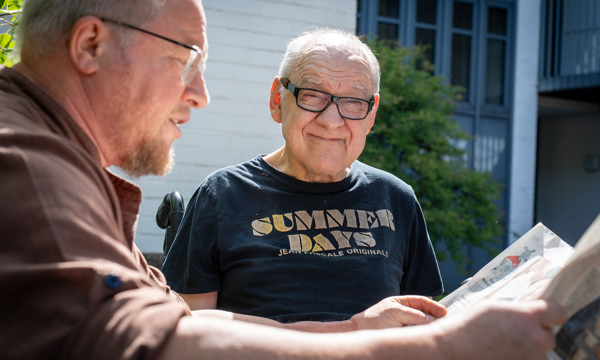 Pflegekraft liest gemeinsam mit einem Bewohner der Einrichtung Zeitung